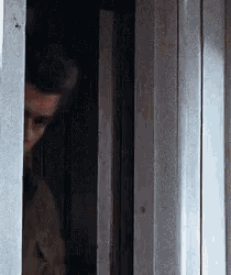 a man is standing in a doorway looking out .