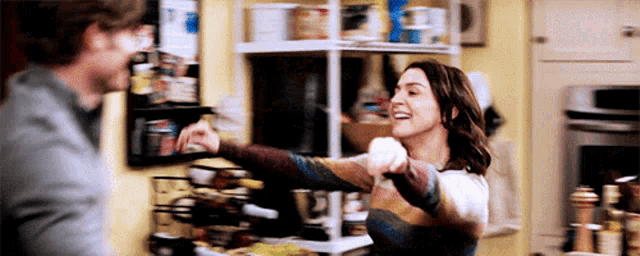 a man and a woman are dancing in a kitchen with a wine rack in the background