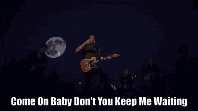 a man singing into a microphone while playing a guitar with the words come on baby don t you keep me waiting below him