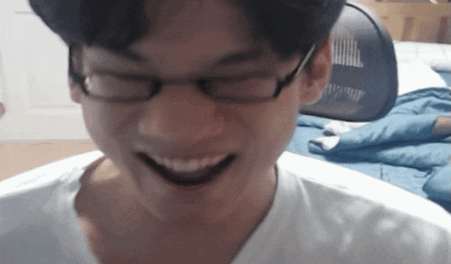 a young man wearing glasses and a white shirt smiles