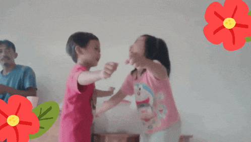 a boy and a girl are dancing in front of a man and flowers