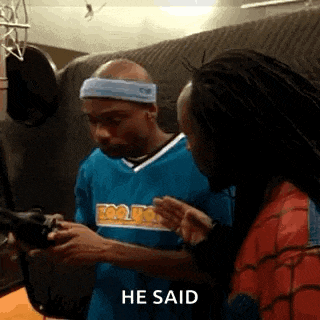 a man wearing a headband is standing next to another man in a spiderman costume .