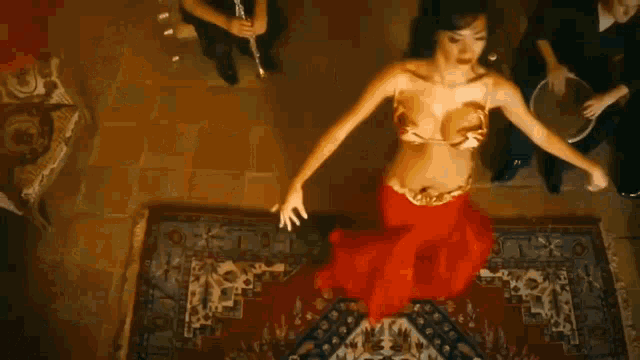 a belly dancer is dancing in a room with a man watching .