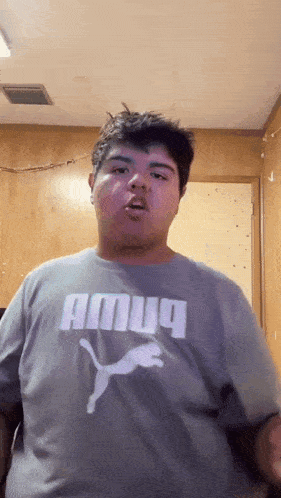a man wearing a gray puma shirt is making a funny face