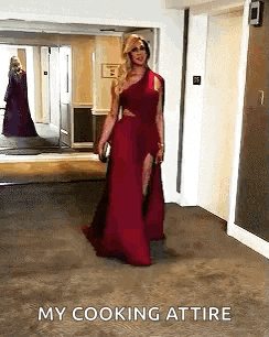 a woman in a red dress is walking down a hallway and says my cooking attire