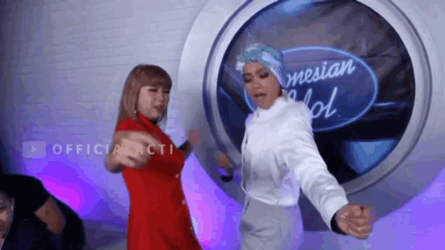 two women are dancing on a stage in front of a screen that says indonesian idol .