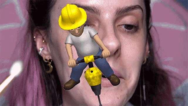 a woman with a yellow hard hat is holding a drill in her mouth