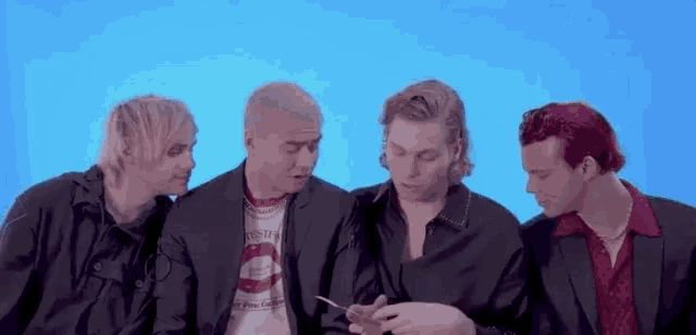 four men are sitting next to each other on a blue background .