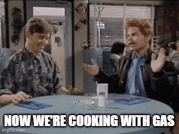 two men are sitting at a table with a caption that says now we 're cooking with gas