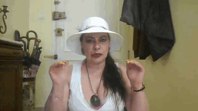 a woman wearing a white hat and a white tank top is making a funny face