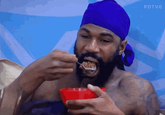 a man with a blue headband is eating cereal from a bowl