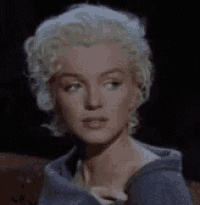 a close up of a woman 's face with blonde hair and a blue shirt .