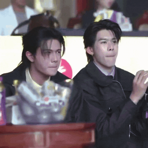 two men are sitting next to each other and one of them is clapping his hands