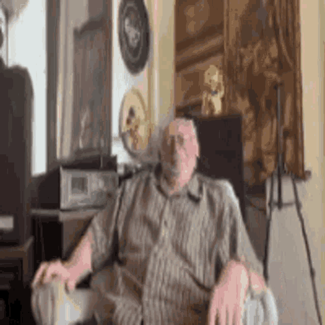 a man in a plaid shirt is sitting in a chair .