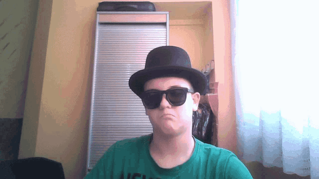 a man wearing a top hat and sunglasses is wearing a green shirt that says ucsd