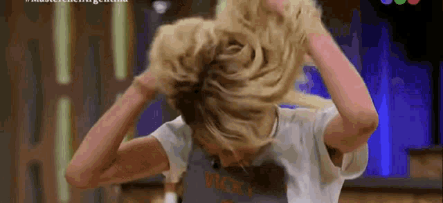a woman is holding her hair in a bun while wearing a vicky t-shirt .
