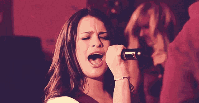 a woman is singing into a microphone with her mouth wide open
