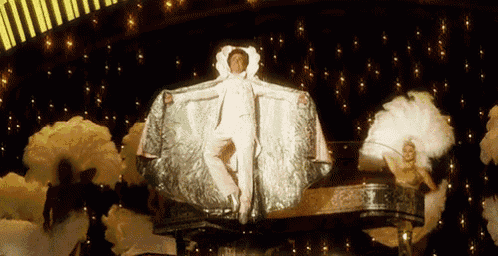 a man in a white cape is standing on a stage