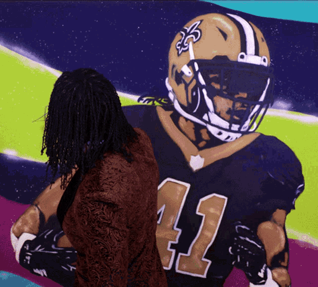 a woman stands in front of a painting of a new orleans saints football player