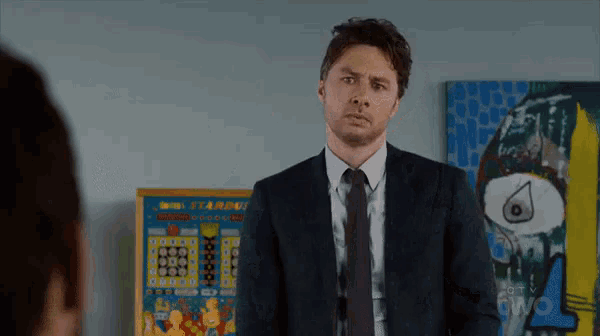 a man in a suit and tie stands in front of a pinball machine that says starburst