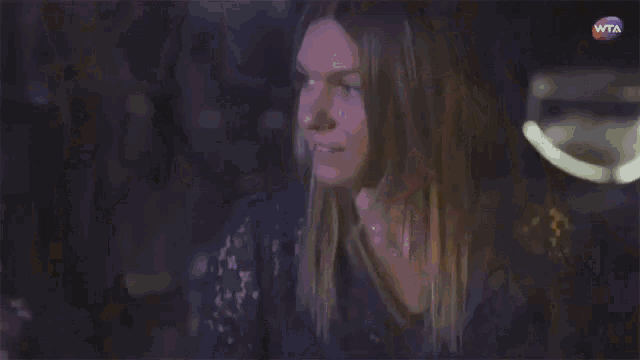 a woman in a dark room with a wta logo in the corner