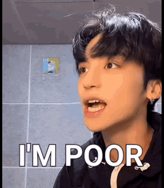 a young man says " i 'm poor " in front of a tiled wall