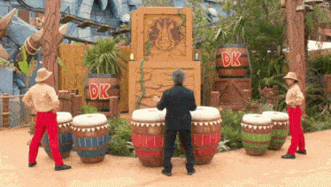 a man playing drums in front of barrels that say dk on them