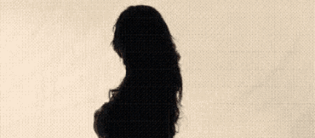 a woman with long black hair is standing in front of a window .