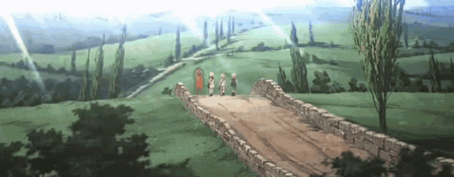 a group of people are walking across a stone bridge in a field