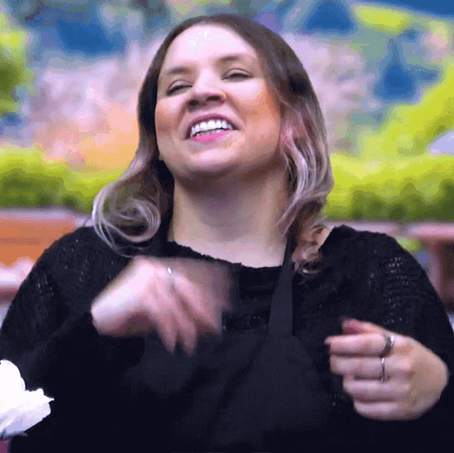 a woman wearing a black sweater is smiling and pointing