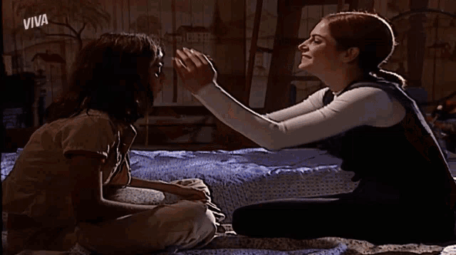 a girl is touching another girl 's face and the word viva is on the bottom