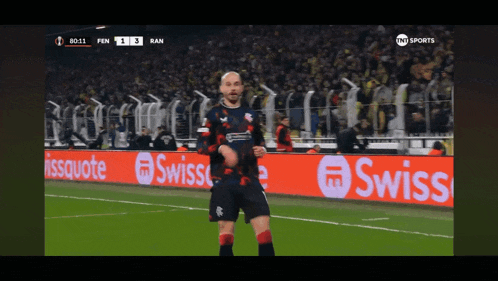a soccer player stands on a field with a swiss advertisement in the background