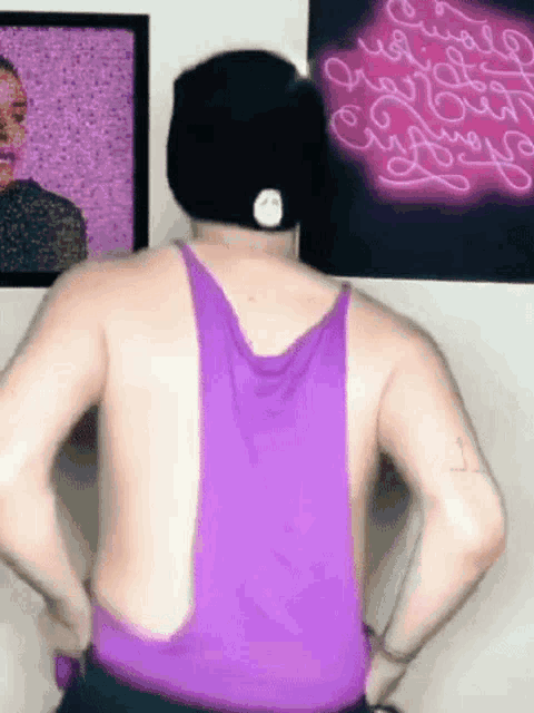 a man is wearing a purple tank top and a hat