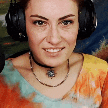a woman wearing headphones and a choker necklace smiles