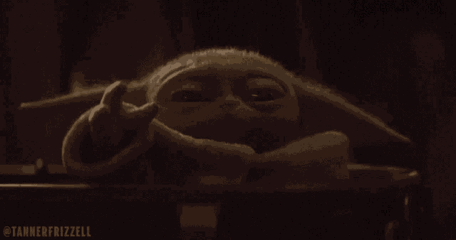a close up of a baby yoda laying in a crib .