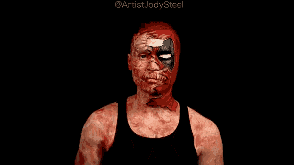 a man with deadpool makeup on his face is making a heart with his hands .