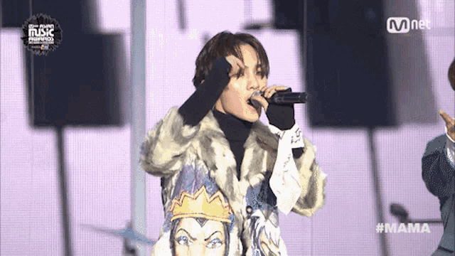a man in a fur coat singing into a microphone with the hashtag mama