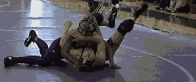two wrestlers are wrestling on a wrestling mat and one of them is wearing nike shoes
