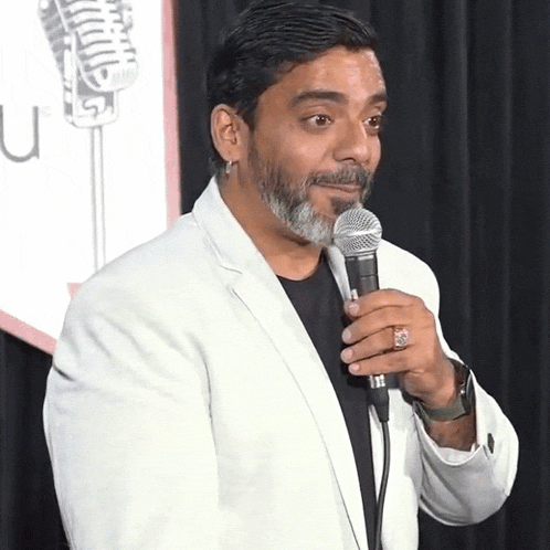 a man in a white jacket is holding a microphone in front of a sign that says u