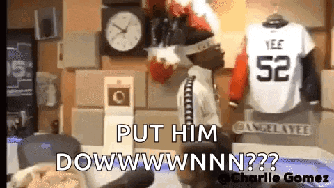 a man is standing in front of a clock and a jersey that says 52 on it .