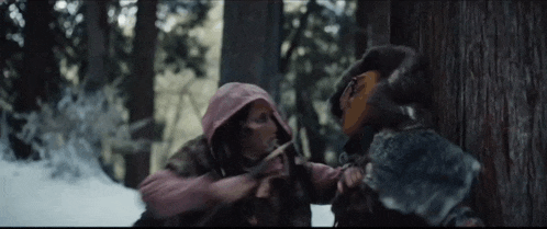 two people are standing next to each other in the woods .