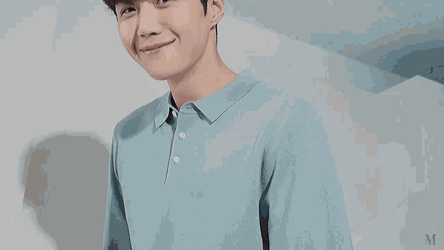 a young man in a blue polo shirt is smiling and looking at the camera .