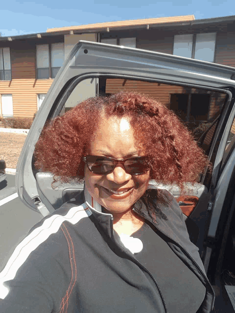 a woman with red hair is smiling while sitting in the back of a car