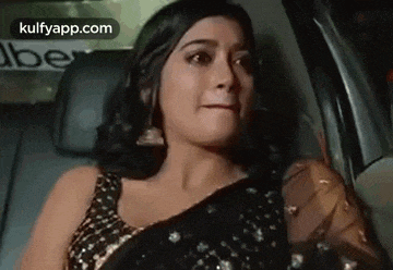 a woman in a saree is sitting in the back seat of a car and crying .