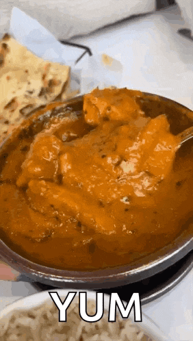a bowl of chicken curry with a spoon in it and the word yum on the bottom