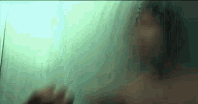 a blurred image of a person taking a shower behind a glass door .