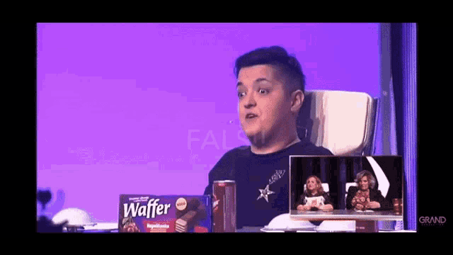 a man is sitting in front of a box of wafer cookies .
