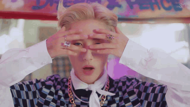 a person covering their eyes with their hands in front of a peace sign