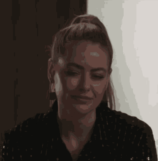 a close up of a woman 's face with her eyes closed and a ponytail