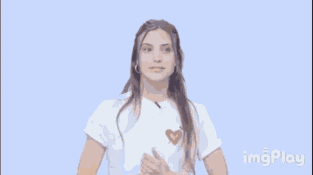 a woman in a white shirt is clapping her hands in front of an emoji of a hand